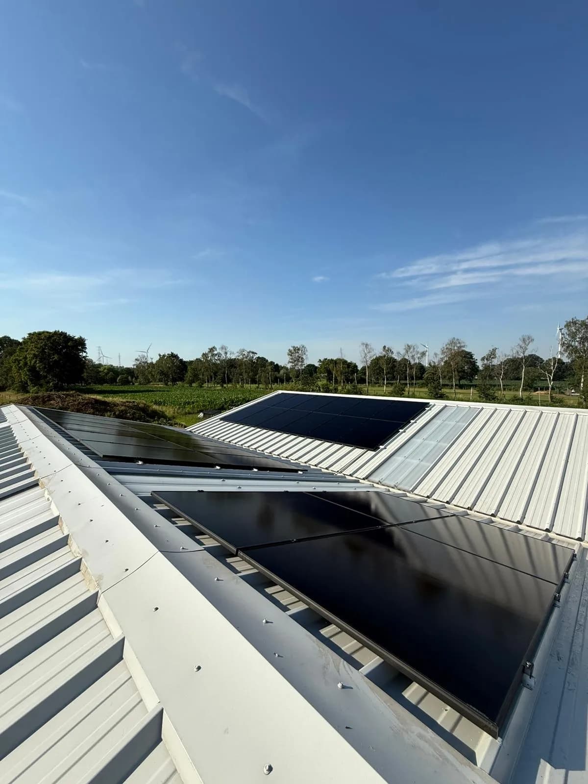 Zonnepanelen op bedrijfsdak met zicht op velden